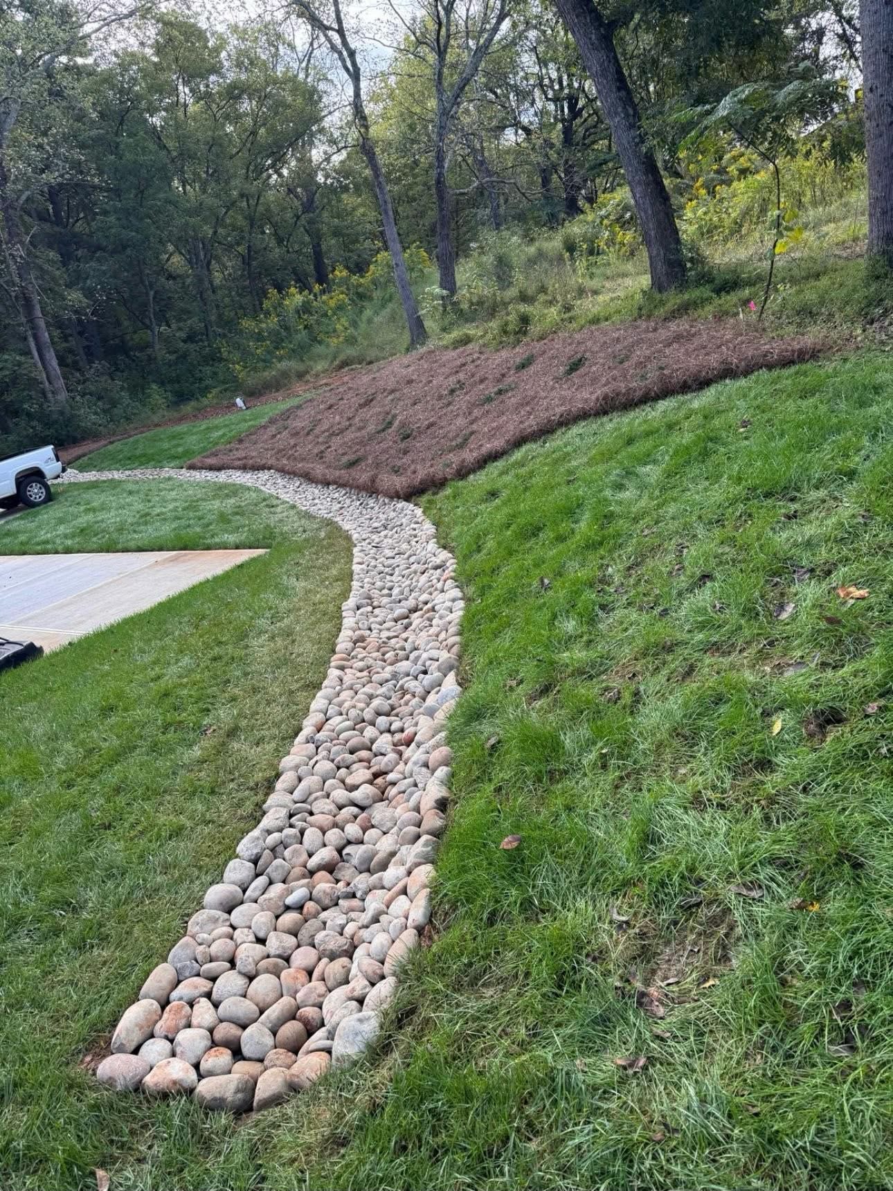 River rock drainage channel through a sloped garden