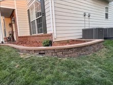 Stone-edged planting bed wrapping around the side of a home