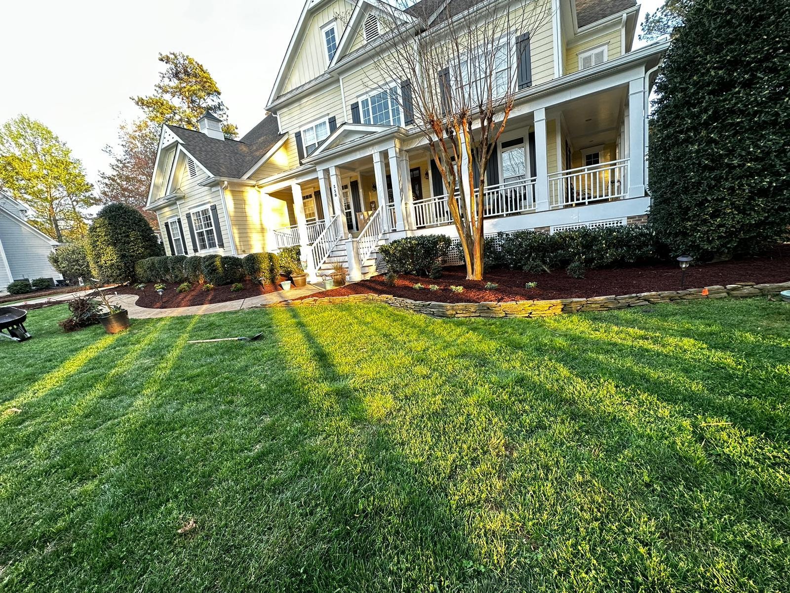 Green front lawn and foundation beds at a yellow home