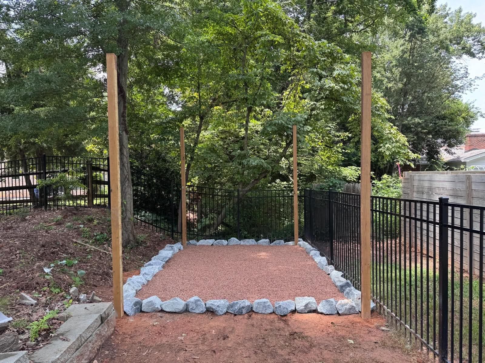 Stone-edged gravel seating area beside a garden fence