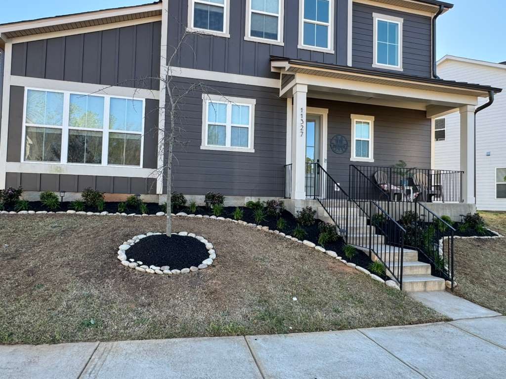 New lawn and circular stone-edged planting bed beside a home