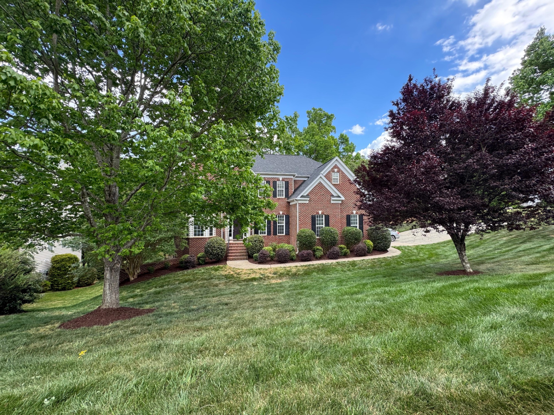 Green lawn and mature trees at a brick home
