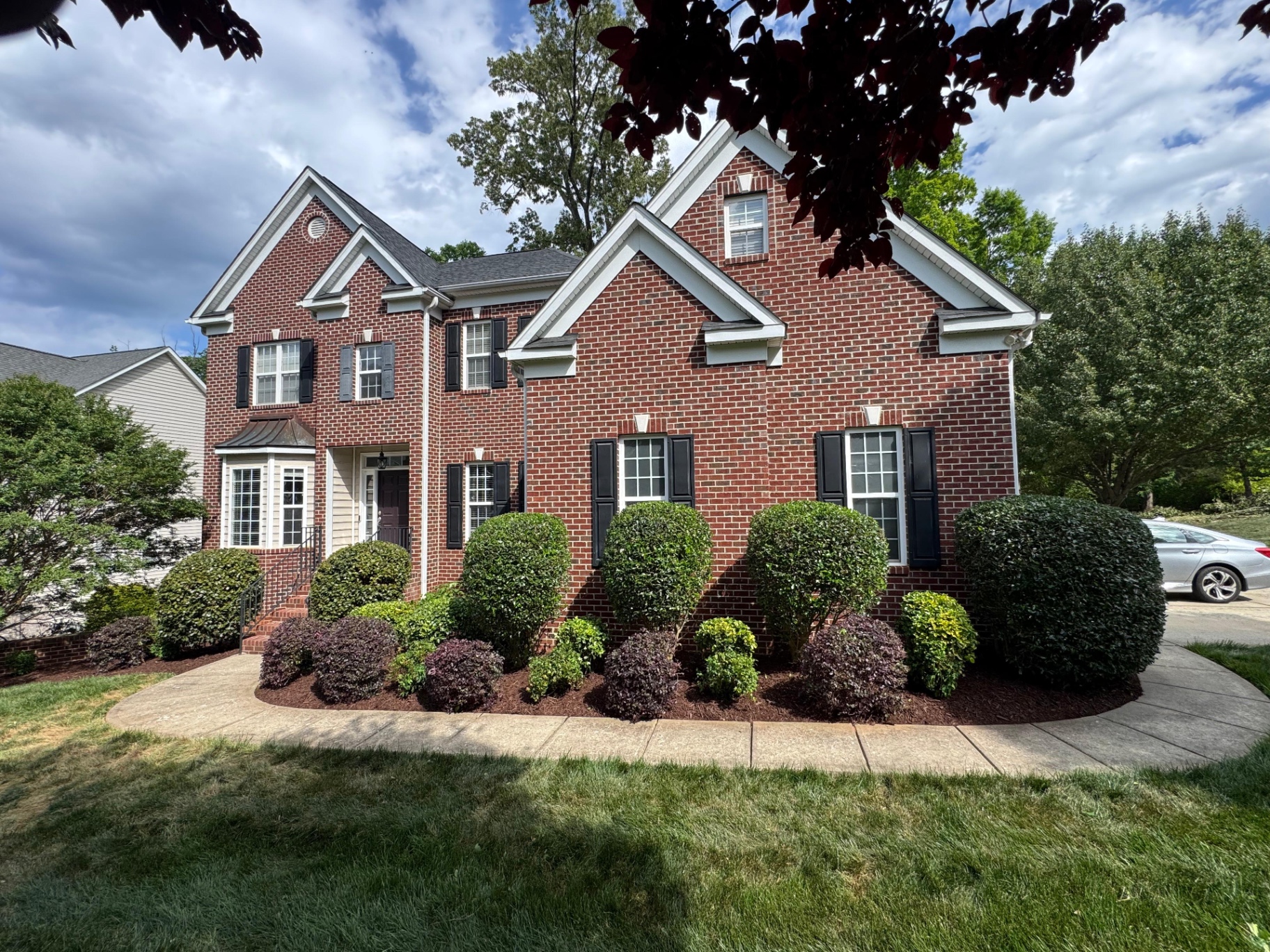 Trimmed shrubs and fresh mulch at a brick home