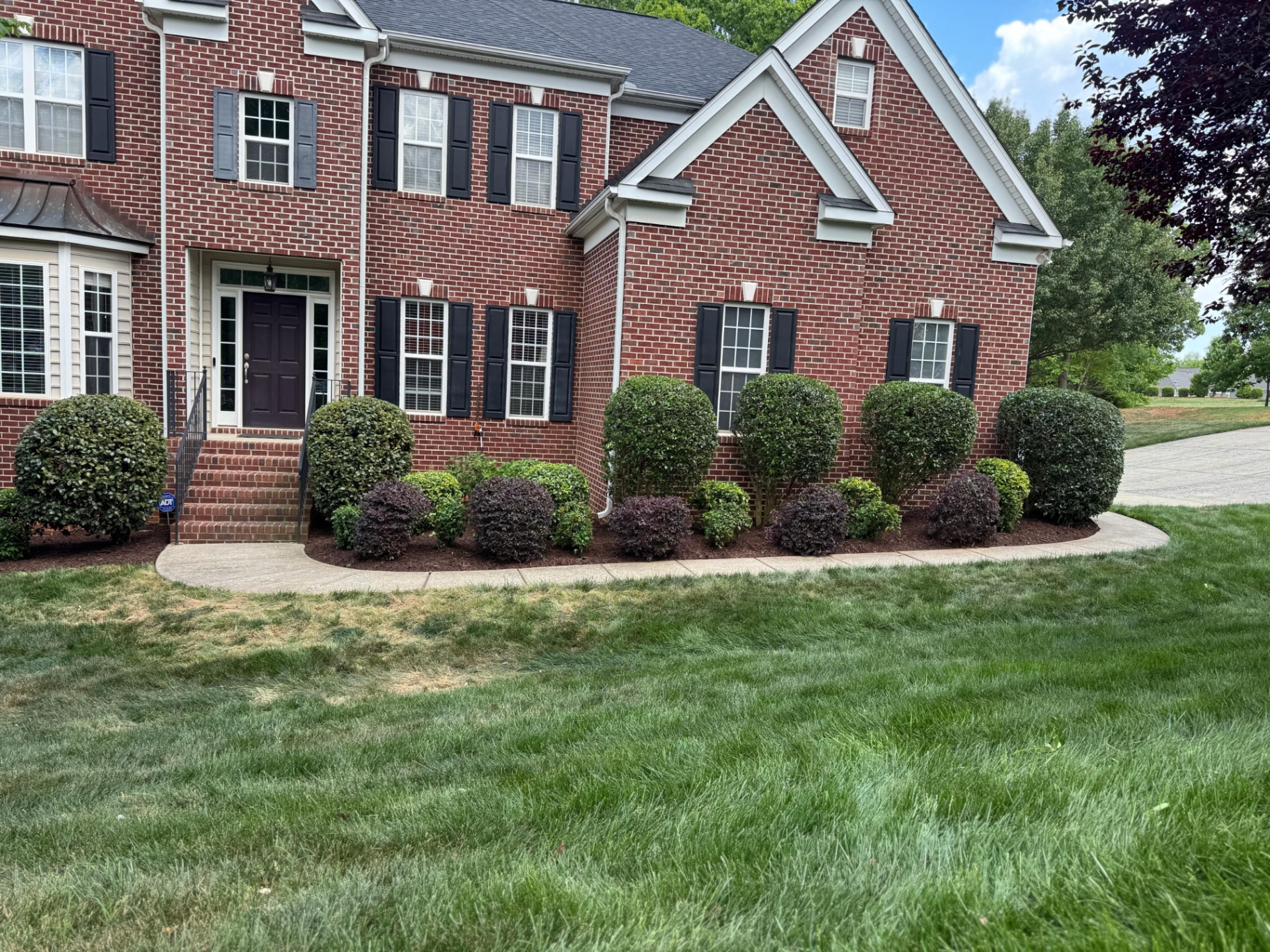 Clipped front shrubs at a brick home