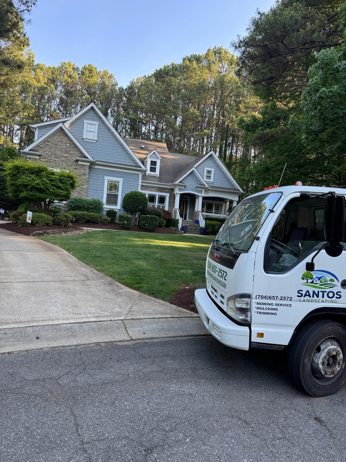 Trimmed foundation shrubs and mulched front beds beside a driveway