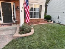 Curved stone garden border beside a front porch and green lawn