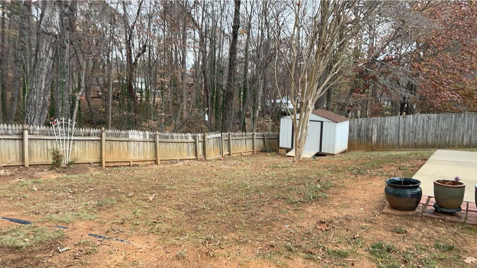 Leaf cleanup along a fenced backyard