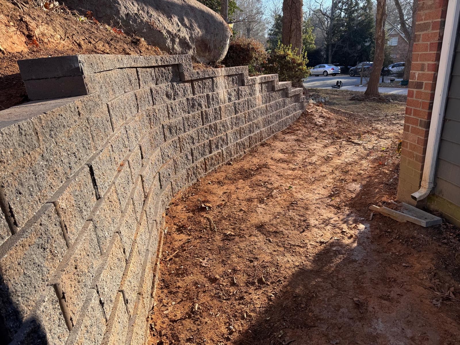 Segmental stone retaining wall beside a sloped garden