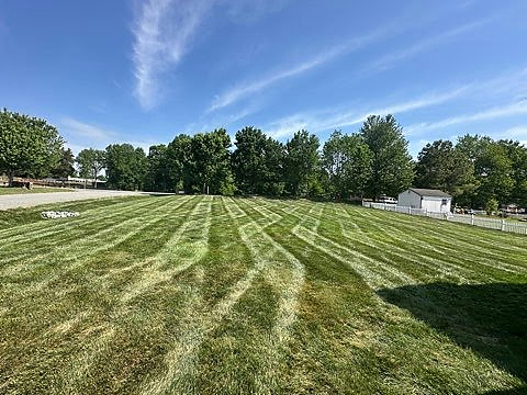 Fresh mowing stripes across an open lawn bordered by mature trees