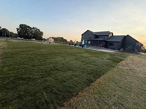 Wide mowed lawn beside a home at sunset